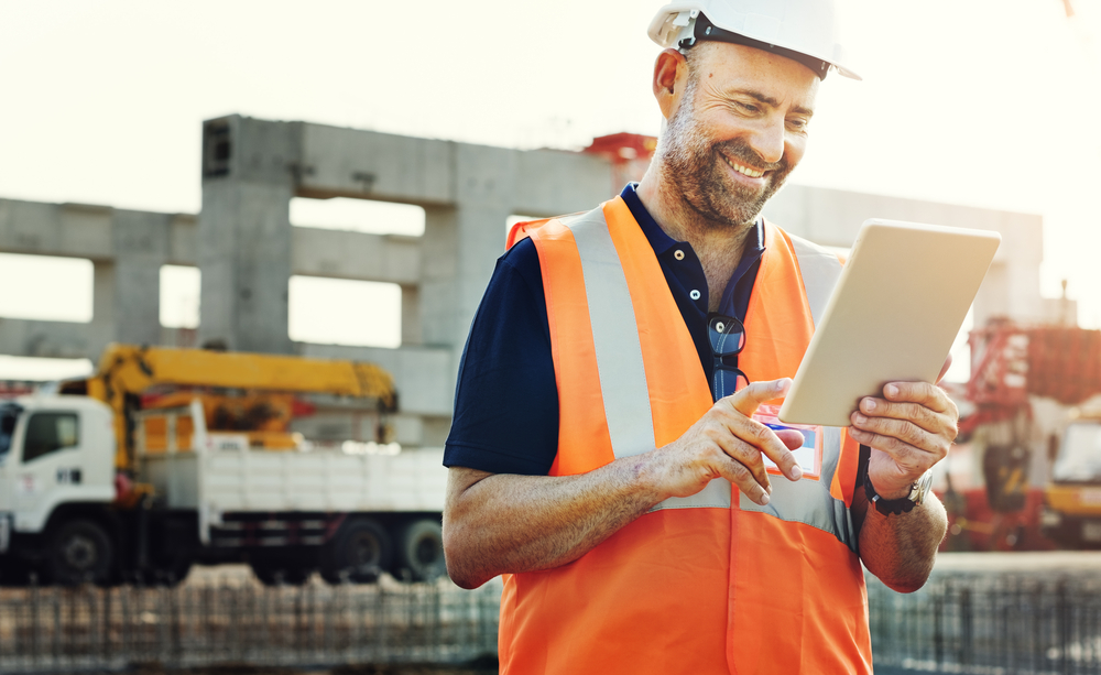 Worker smiles while viewing data table at a construction site
